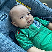 Ethan joined the competition — help win amazing prizes! baby, child, car_seat, green_shirt, mexico_jersey, infant, cute, pout, serious_expression, clothing, seatbelt, car_interior, portrait, person, young_child, indoors, closeup, head_and_shoulders, fabric, casual