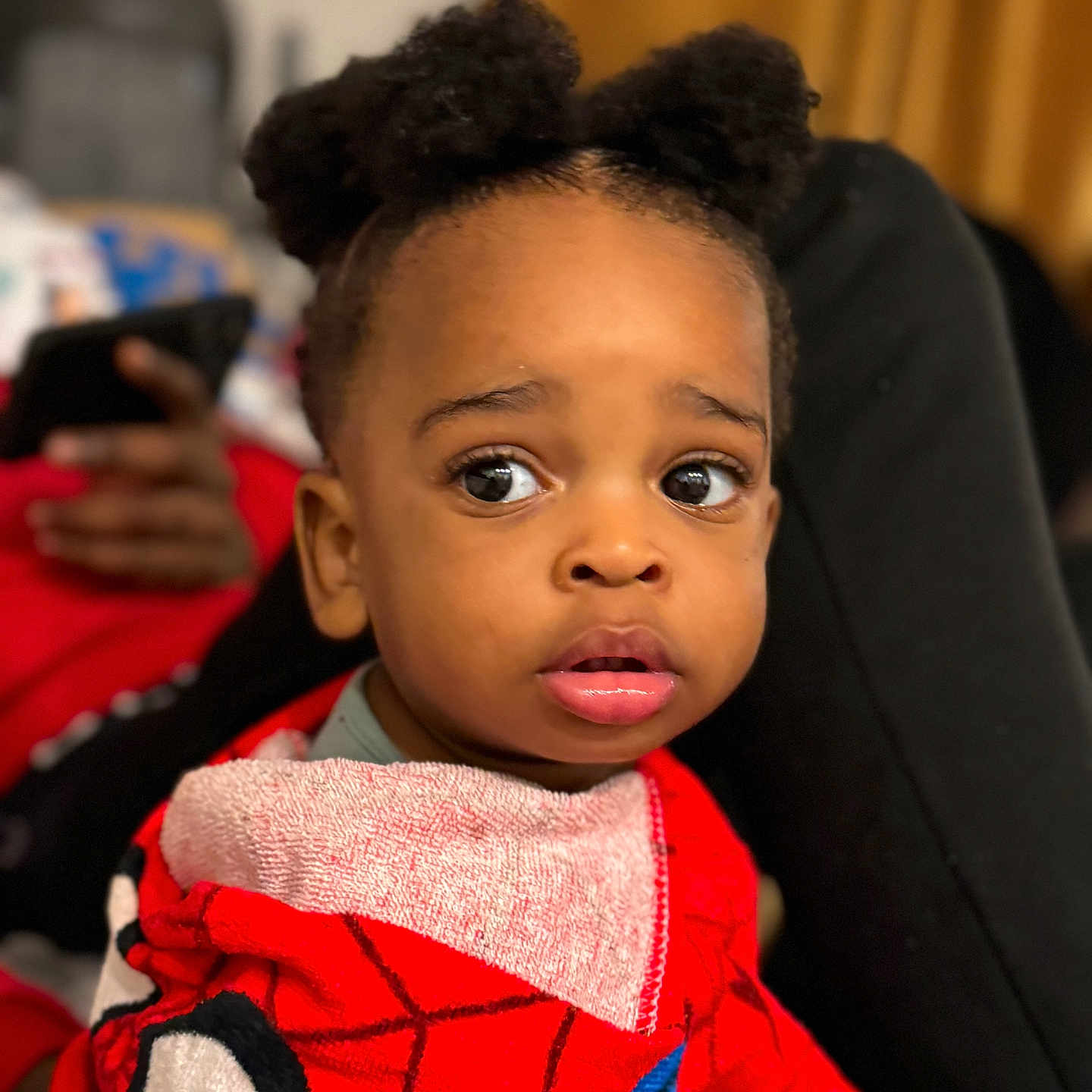 Jabari a rejoint le concours — aidez-le/la à gagner de superbes lots ! baby, bib, big_eyes, child, couch, curious_expression, curtain, face, hair_puffs, hand, indoors, lip_gloss, pigtails, portrait, red_clothing, skin_tone, smartphone_background, spiderman, toddler, towel