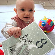 Inaya a rejoint le concours — aidez-le/la à gagner de superbes lots ! baby, child, clothing, colorful, cute, floor, fox_illustration, hand, indoors, infant, milestone_card, months_old, number_8, pink, play_mat, portrait, sitting, smiling, toy, white