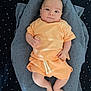 baby, infant, child, peach_clothing, blanket, blue_blanket, star_pattern, lying_down, soft_fabric, cute, portrait, indoors, newborn, smiling, human, person, relaxing, comfort, sleepwear, toddler
