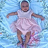 Kaylyn is registered to the contest to win money with this photo: baby, infant, child, pink_dress, headband, blanket, floral_pattern, lying_down, cute, portrait, small_hands, small_feet, indoors, soft_lighting, peaceful, adorable, newborn, person, clothing, baby_girl