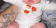 Brooklyn is registered to the contest to win money with this photo: baby, infant, onesie, pumpkin, tattoo, arm, leg, foot, toe, skin, person, holding, clothing, cute, indoors, closeup, portrait, child, newborn, white