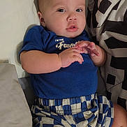 Zachariah joined the competition — help win amazing prizes! baby, child, infant, blue_shirt, checkered_shorts, pillow, bed, bedding, hand, face, eyes, skin, comfort, indoor, person, cute, young, portrait, relaxing, clothing