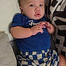baby, child, infant, blue_shirt, checkered_shorts, pillow, bed, bedding, hand, face, eyes, skin, comfort, indoor, person, cute, young, portrait, relaxing, clothing