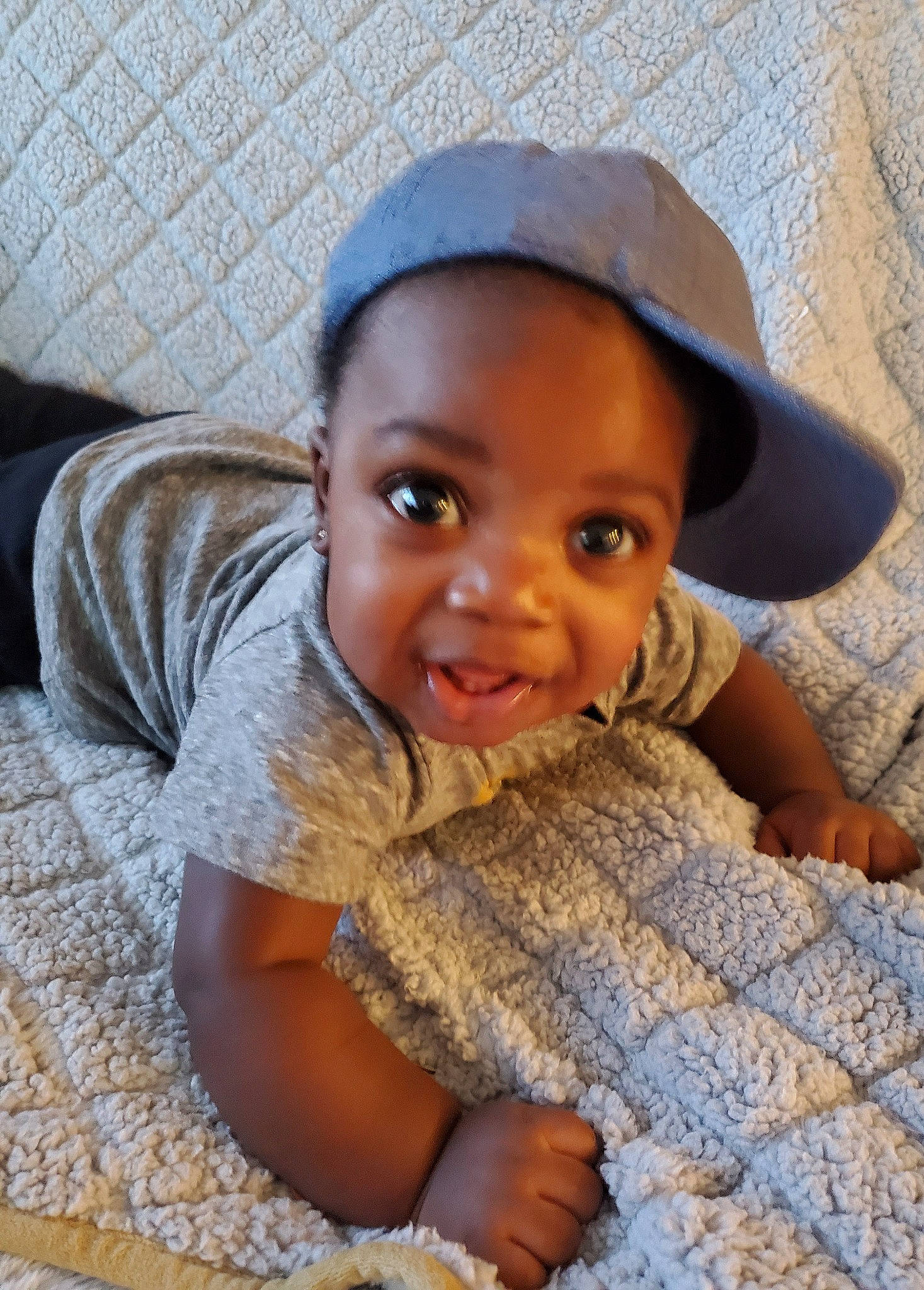 Shamari is registered to the contest to win money with this photo: arm, baby_toddler_clothing, cap, child, chin, comfort, eye, facial_expression, finger, flooring, fun, hairstyle, happy, mammal, nose, people, person, skin, smile, toddler