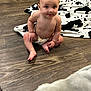 Jackson joined the competition — help win amazing prizes! baby, child, diaper, floor, wood_floor, blanket, cow_print, indoor, sitting, tongue_out, cute, infant, person, skin, face, expression, playful, looking_at_camera, young, human