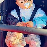 Timéo participe au concours pour gagner de l'argent avec cette photo : baby, child, stroller, pacifier, plush_toy, clothing, glasses_filter, bear_ears_filter, heart_effects, cute, sitting, comfort, straps, footwear, pants, jacket, toy, indoors, portrait, person