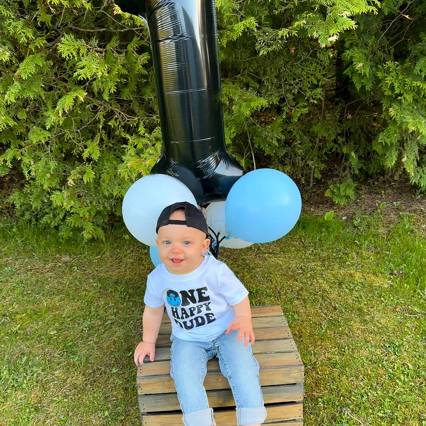 Jensen joined the competition — help win amazing prizes! baby, balloon, barefoot, blue_balloon, boy, cap, casual_clothing, celebration, child, daylight, grass, greenery, happy, number_one, outdoor, portrait, shirt, smiling, white_balloon, wooden_crate