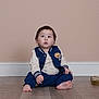 Jayden is registered to the contest to win money with this photo: baby, child, toddler, sitting, floor, blue_clothing, jacket, long_sleeves, barefoot, indoor, wooden_floor, curious_expression, short_hair, light_skin, casual_wear, portrait, young_child, studio, neutral_background, cute