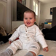 Kaylee a rejoint le concours — aidez-le/la à gagner de superbes lots ! baby, smiling, white_pajamas, elephant_design, gray_socks, toys, living_room, television, couch, blanket, floor, window, natural_light, happy, infant, child, person, indoor, seated, cute