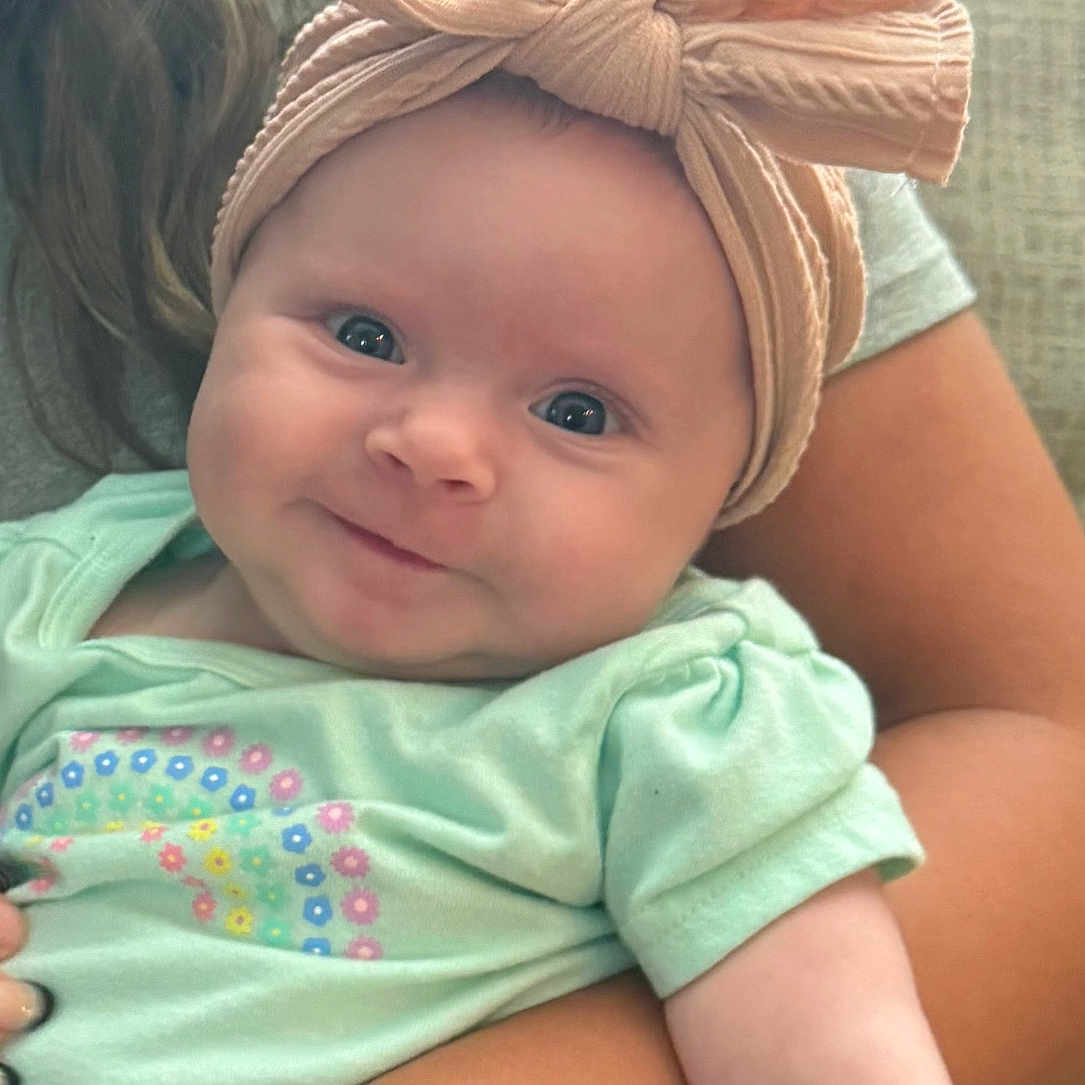 Eliza joined the competition — help win amazing prizes! arm, baby, bow, child, clothing, cute, face, happy, headband, holding, indoor, infant, pastel_colors, person, portrait, sitting, skin, smile, toddler, young