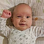 baby, infant, smile, face, arm, blanket, stars, clothing, onesie, cute, happy, lying_down, skin, head, expression, child, newborn, person, indoors, closeup