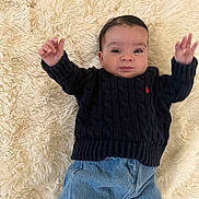 Gianna participe au concours pour gagner de l'argent avec cette photo : baby, infant, child, sweater, jeans, white_shoes, fluffy_rug, textured_rug, indoor, portrait, cute, raising_arms, clothing, young_child, person, lying_down, casual_wear, home, soft_texture, cozy