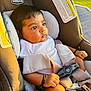 baby, car_seat, chicco, infant, child, safety_harness, sunlight, outdoor, seatbelt, clothing, face, person, hand, arm, leg, sitting, expression, closeup, warning_label, restraint