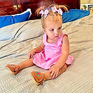 Clarissa joined the competition — help win amazing prizes! toddler, child, girl, pink_dress, hair_bows, bed, blanket, sandals, wooden_headboard, pillow, indoor, curious_expression, framed_photos, nightstand, home, sitting, footwear, cute, young_child, portrait