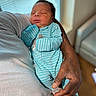 newborn, baby, infant, sleeping, portrait, indoors, onesie, turquoise, striped_clothing, adult, hand, arm, tattoo, cradled, couch, blanket, window, blinds, peaceful, family