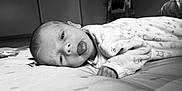 Ezio a rejoint le concours — aidez-le/la à gagner de superbes lots ! baby, blanket, child, clothing, cute, expression, face, head, high_chair, indoor, infant, lying_down, monochrome, pattern, playful, portrait, room, sleepwear, soft_lighting, tongue_out
