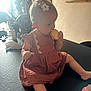 toddler, child, biscuits, dress, hair_clip, indoor, table, flower, plant, window, natural_light, curly_hair, snack, pink, sitting, skin, face, hand, legs, cozy
