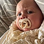 baby, pacifier, face, infant, lace, clothing, blanket, cushion, pattern, closeup, portrait, soft, texture, indoor, child, cute, expression, newborn, resting, cozy