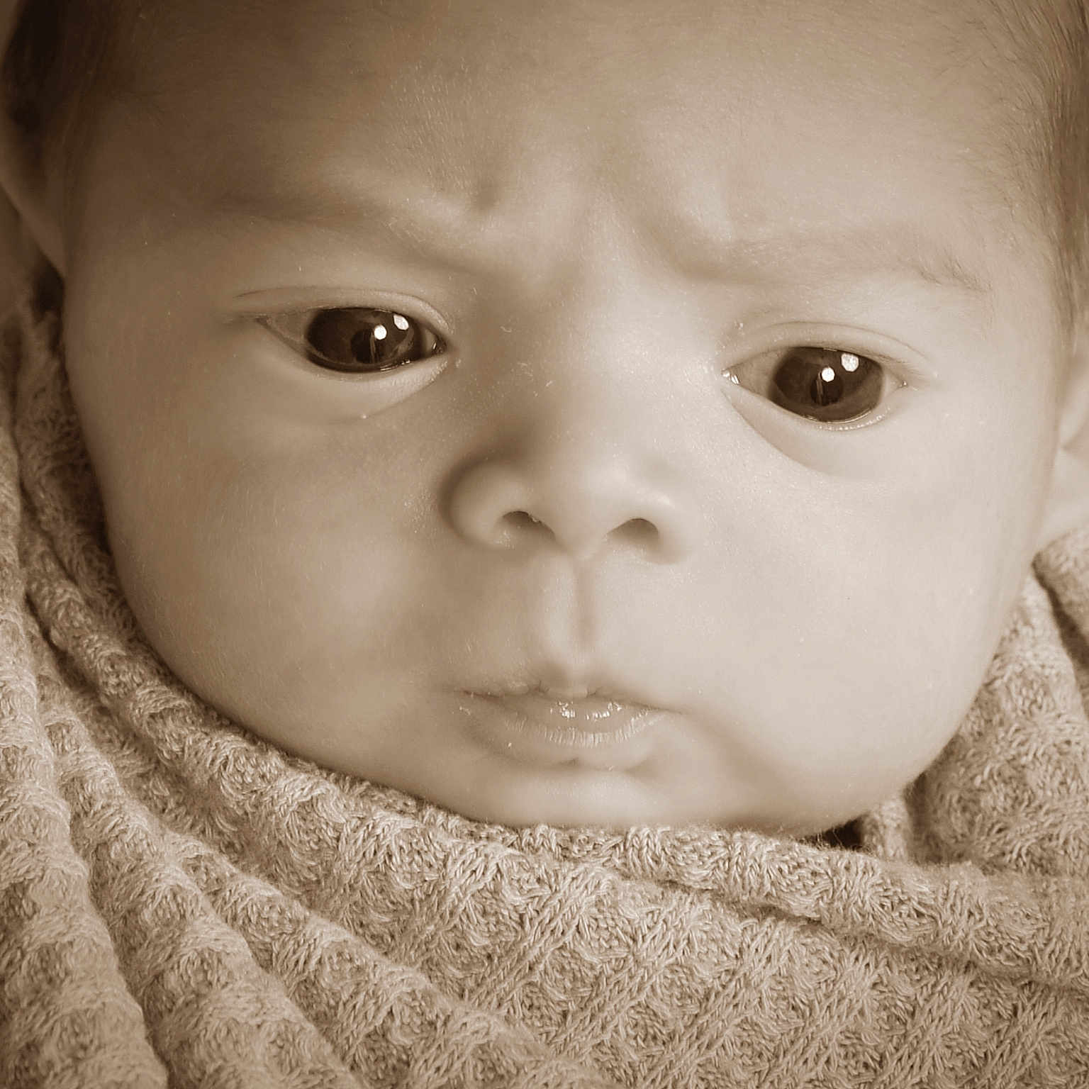 Neo is registered to the contest to win money with this photo: baby, bathtowel, bonnet, clothing, face, frown, hat, head, knitwear, newborn, person, photography, portrait, sad, sweater, towel