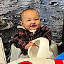 baby, child, smile, plaid_shirt, astronaut_helmet, rocket_plush, space_theme, lunar_surface, planet, indoor, chair, cute, portrait, happy, infant, toy, costume, playful, background, person
