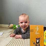 Menzo a rejoint le concours — aidez-le/la à gagner de superbes lots ! age_card, baby, carpet, child, clothing, cute, face, floor, happy, head, indoor, infant, lying_down, milestone_card, person, playful, portrait, rug, smiling, toy