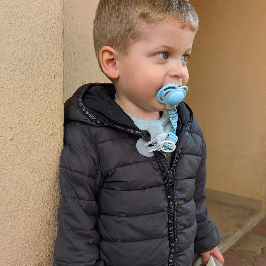 Kaylann participe au concours pour gagner de l'argent avec cette photo : beige_wall, black_jacket, blue_pants, boy, casual_clothing, child, curious, cute, daylight, holding, looking_away, outdoor, pacifier, pavement, portrait, short_hair, standing, stuffed_cloth, toy, young_child