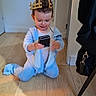 Mya a rejoint le concours — aidez-le/la à gagner de superbes lots ! baby, bag, chair_leg, child, crown, curtain, doorway, hardwood, indoor, onesie, pajamas, paper_crown, phone, playing, sitting, smartphone, smiling, toddler, wall, wooden_floor