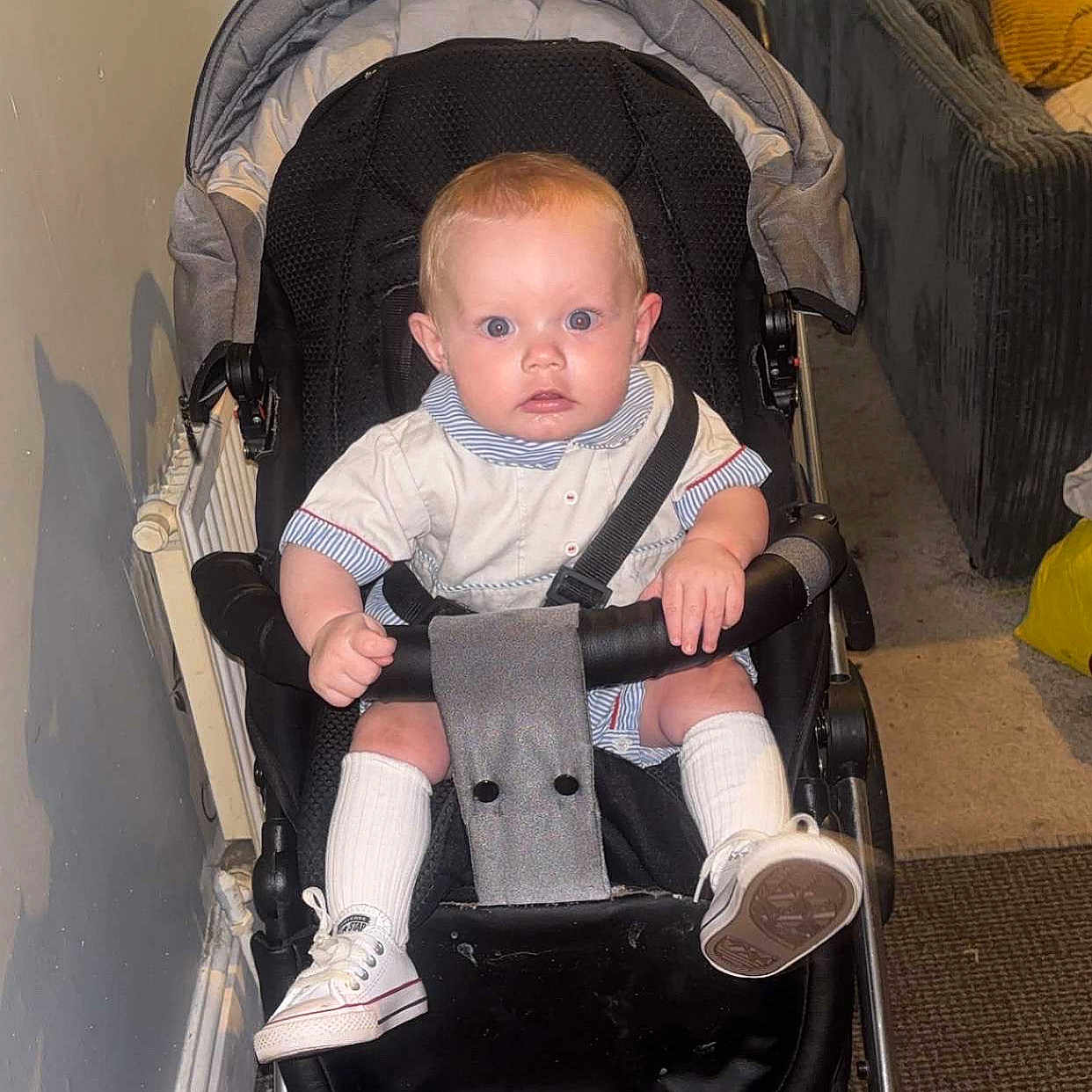 Teddy Keith joined the competition — help win amazing prizes! baby, carpet, carriage, child, clothing, couch, curious, expression, face, floor, hands, indoor, person, radiator, seatbelt, seated, shoes, socks, stroller, wall