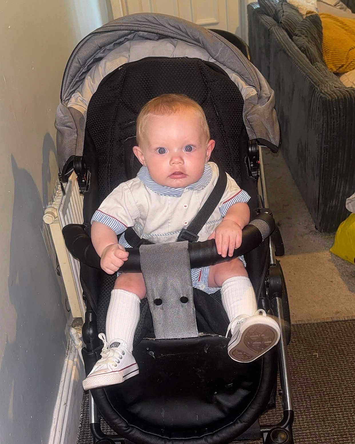 Teddy Keith joined the competition — help win amazing prizes! baby, stroller, indoor, child, socks, shoes, face, hands, clothing, seatbelt, carriage, person, floor, wall, radiator, couch, carpet, curious, expression, seated