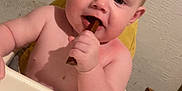 Teddy Keith joined the competition — help win amazing prizes! baby, child, high_chair, chewing, chocolate, food, indoor, person, furniture, table, skin, face, hand, head, cute, young, infant, smiling, seat, background