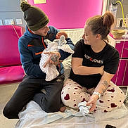 Teddy Keith joined the competition — help win amazing prizes! baby, newborn, father, mother, hospital, blanket, beanie, tattoo, pajamas, smiling, family, indoor, bed, phone, furniture, medical, parent, person, happy, love