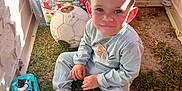 Iyed a rejoint le concours — aidez-le/la à gagner de superbes lots ! boots, boy, child, clothing, container, face, floor, grass, hair, hand, indoor, light, plastic, play, playhouse, shadow, sitting, smiling, soccer_ball, toy_car