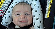 Weston is registered to the contest to win money with this photo: baby, car_seat, blanket, dinosaur, headrest, infant, smile, child, seatbelt, polka_dot, cute, face, indoors, safety, happy, clothing, portrait, infant_care, transportation, comfort