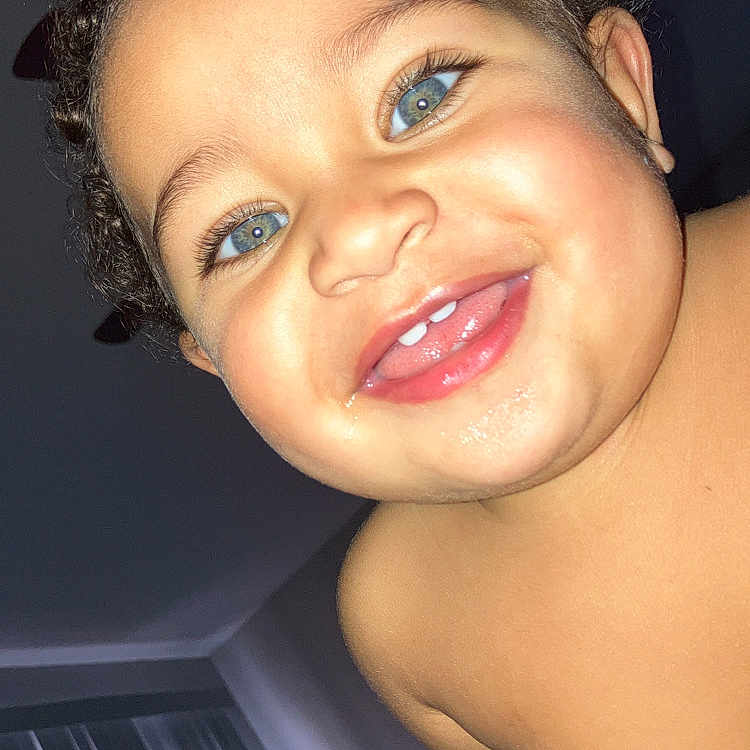 Jazmin is registered to the contest to win money with this photo: baby, background, blue_eyes, cheek, child, close_up, curly_hair, face, happy, head, indoor, mouth, person, portrait, shoulder, skin, smiling, teeth, toddler, tongue