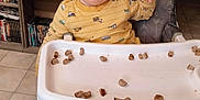 Austin joined the competition — help win amazing prizes! blue_eyes, bookshelf, child, dvd_cases, expression, face, floor_tiles, food_pieces, footwearless, furniture, high_chair, home, indoor, person, playful, seated, smiling, toddler, tray, yellow_pajamas
