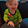 bright_colors, child, couch, face, furniture, green_clothing, hair, hand, happy, home, indoor, living_room, pajamas, person, playful, sitting, smiling, television, toddler, young_child