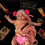 baby, beauty_products, black_background, child, cosmetics, cute, face, fluffy_hat, hat, high_heel_shoe, indoor, lying_down, makeup_brush, perfume_bottle, person, pink, pom_poms, relaxing, skin, towel