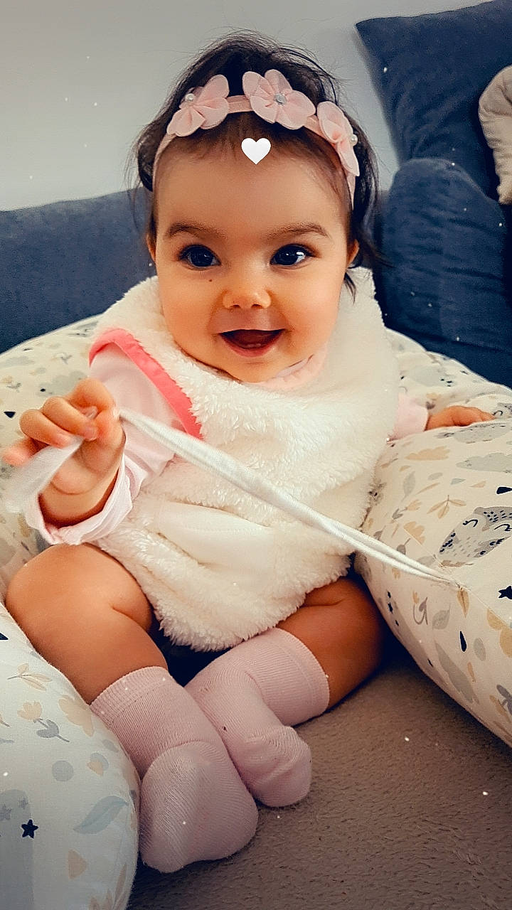 Luisa participe au concours pour gagner de l'argent avec cette photo : baby, baby_toddler_clothing, cheek, child, chin, comfort, dress, eye, eyebrow, finger, gesture, happy, headgear, iris, joy, lip, person, pink, skin, sleeve