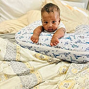 Tru joined the competition — help win amazing prizes! baby, infant, pillow, bed, blanket, patterned_blanket, dinosaur_pattern, cute, face, arms, curious, indoors, soft_lighting, cozy, resting, person, child, sleeping_area, textile, comfortable