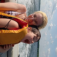 Raffael joined the competition — help win amazing prizes! child, adult, life_jacket, boat, water, lake, sky, clouds, smile, happy, summer, outdoor, nature, fun, safety, glasses, hair, sitting, excitement, family