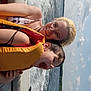 child, adult, life_jacket, boat, water, lake, sky, clouds, smile, happy, summer, outdoor, nature, fun, safety, glasses, hair, sitting, excitement, family