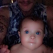 Oakley joined the competition — help win amazing prizes! adult, baby, blue_eyes, casual, child, closeup, dim_lighting, drool, expression, face, holding, indoor, looking_up, patterned_clothing, person, portrait, shadow, skin, sleeveless_shirt, tattoos