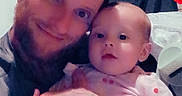 Oakley joined the competition — help win amazing prizes! baby, background_objects, ball, casual_clothing, child, curious, diaper, face, hat, holding, home, indoor, man, parent_and_child, person, portrait, seated, smiling, tattoo, wooden_wall