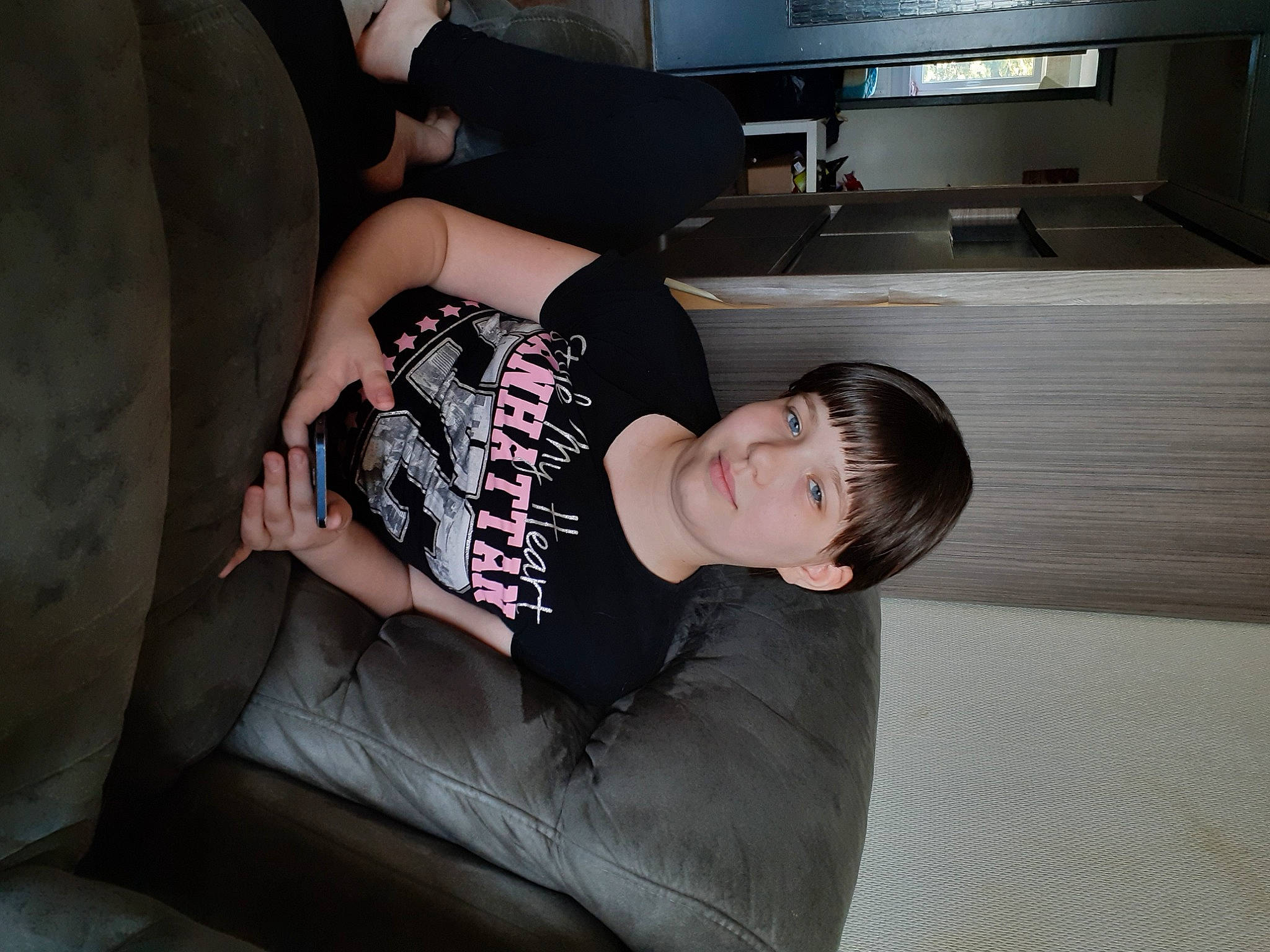 Mélinda a rejoint le concours — aidez-le/la à gagner de superbes lots ! automotive_design, black_hair, comfort, couch, display_device, elbow, eyewear, flash_photography, flooring, fun, home_appliance, human_leg, knee, lighting, living_room, person, room, sitting, t_shirt, thigh