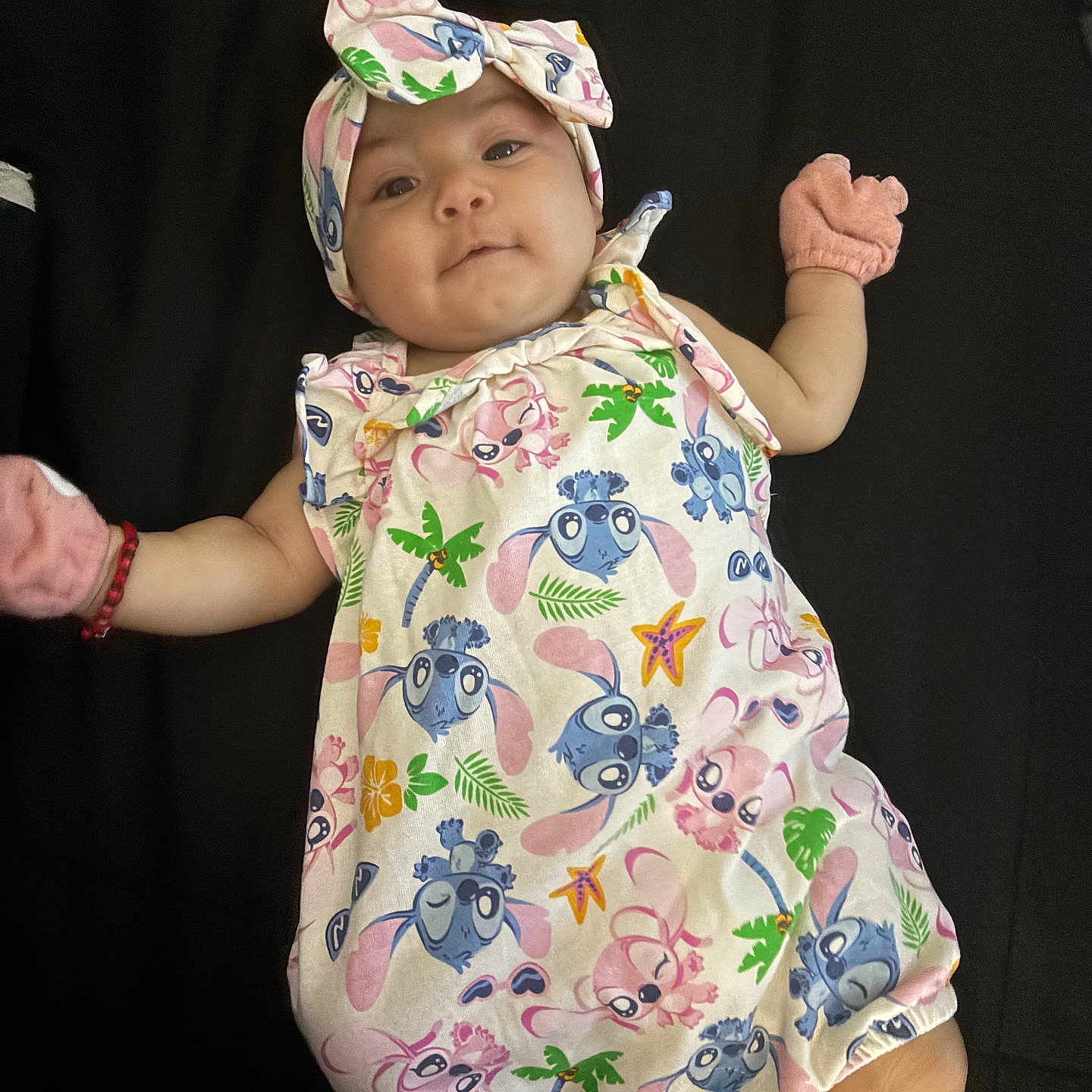 Gitzel is registered to the contest to win money with this photo: baby, blue, cartoon_print, child, colorful_clothing, cute, expression, face, green, headband, indoors, infant, lying_down, mittens, onesie, palm_tree, person, pink, starfish, yellow