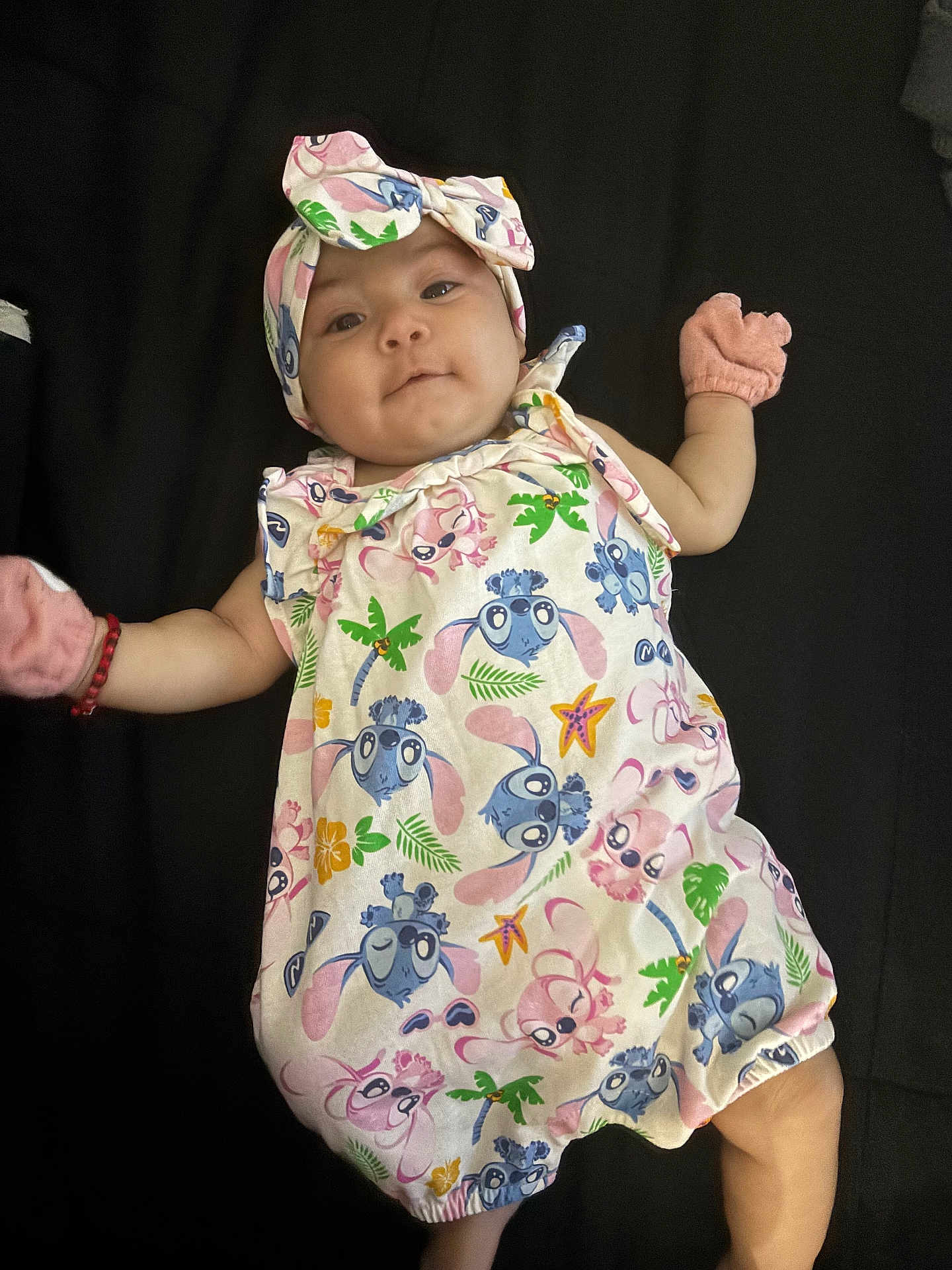 Gitzel is registered to the contest to win money with this photo: baby, blue, cartoon_print, child, colorful_clothing, cute, expression, face, green, headband, indoors, infant, lying_down, mittens, onesie, palm_tree, person, pink, starfish, yellow
