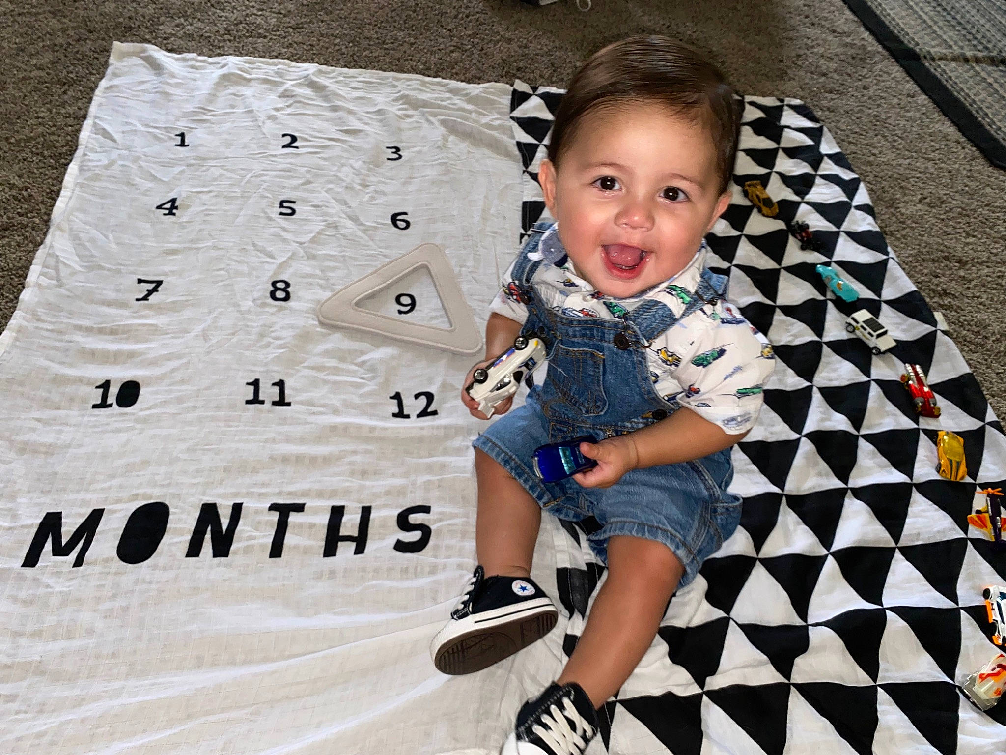 Kalvin is registered to the contest to win money with this photo: baby, baby_toddler_clothing, child, cool, design, electric_blue, eye, flooring, font, fun, happy, human_leg, mammal, pattern, person, product, sitting, sleeve, smile, t_shirt