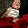 baby, sleeping, blanket, red_blanket, couch, white_shirt, butterflies, child, resting, indoor, relaxation, cozy, peaceful, portrait, infant, hand, face, soft_lighting, comfort, home