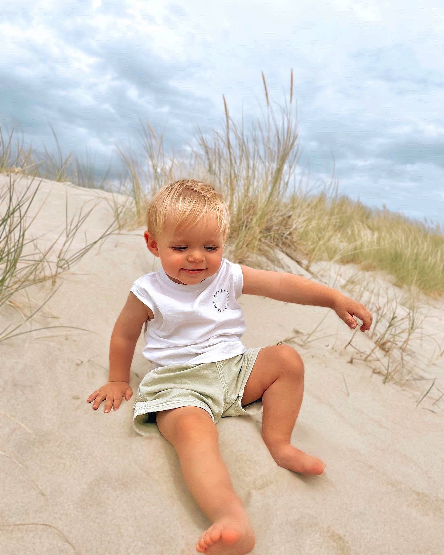 Nélio participe au concours pour gagner de l'argent avec cette photo : baby, baby_toddler_clothing, barefoot, beach, child, cloud, foot, fun, grass, happy, human_leg, joy, landscape, leisure, people_in_nature, person, plant, sand, sitting, sky